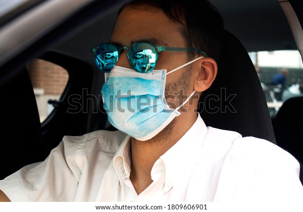 man
inside the car with face mask and the window
down
