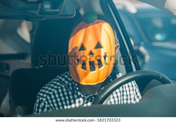 Man inside a car with a pumpkin mask of jack o\
lantern Hallowwen