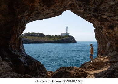 Man inside cave, view Lighthouse Portocolom in Mallorca.