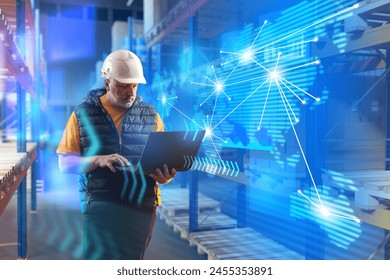 Man inside logistics warehouse. Logistician with laptop in work uniform. Employee of modern warehouse. Logistician uses specialized software. Man warehouse manager among racks with pallets