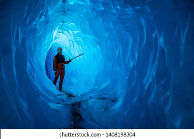 Man inside a melting glacier ice cave. Cut by water from the warming, melting glacier, the cave runs deep into the ice of the Matanuska Glacier in Alaska.
