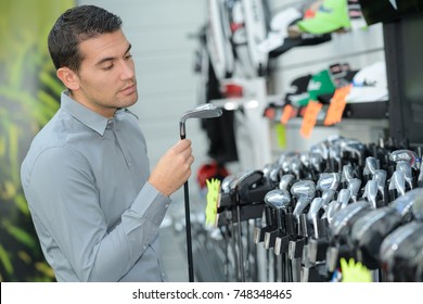 Man Inspecting The Golf Clubs