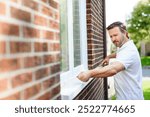 A man inspecting house window outside on day light