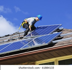 Man Installing Alternative Energy Photovoltaic Solar Panels On Roof