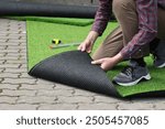 Man installing artificial turf outdoors, closeup view