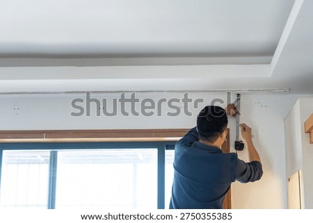 Man installing ceiling trim in modern home interior, urban residential renovation project
