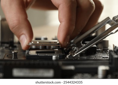 Man installing computer chip onto motherboard at table, closeup