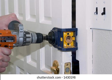 A Man Is Installing A Dead Bolt For Added Security