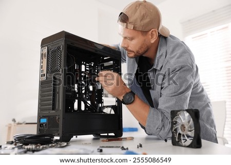 Man installing fan into computer at white table