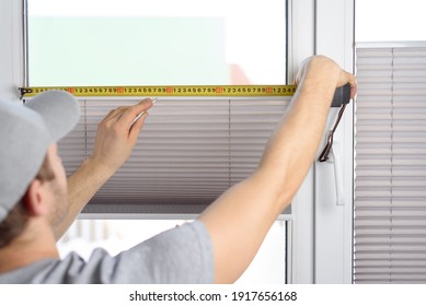 Man Installing Gray Pleated Blinds On The Window