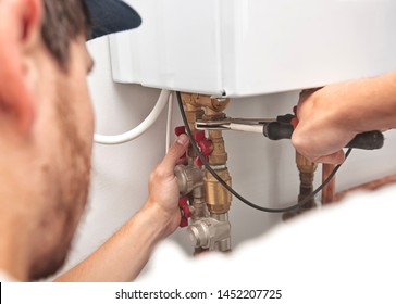 The man is installing the heater system in the house and checking pipes by the wrench