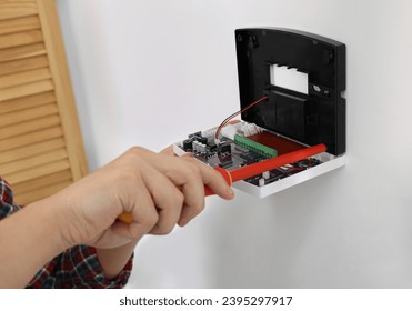 Man installing home security alarm system on white wall indoors, closeup - Shutterstock ID 2395297917