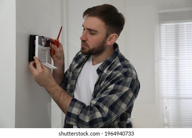 Man Installing Home Security System On White Wall In Room