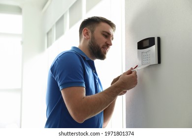 Man Installing Home Security System On White Wall In Room