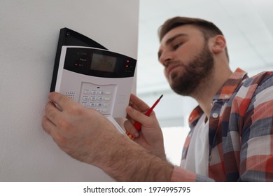 Man installing home security system on white wall in room - Shutterstock ID 1974995795
