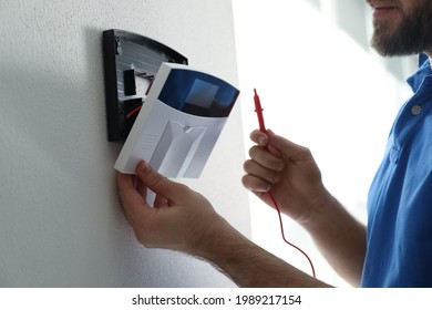 Man Installing Home Security System On White Wall In Room, Closeup