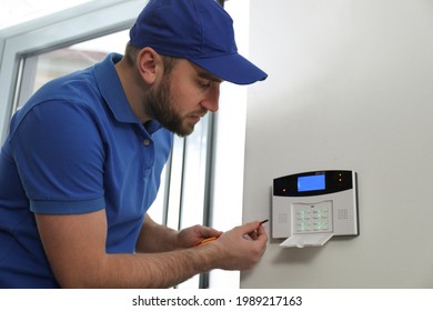 Man Installing Home Security System On White Wall In Room