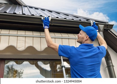man installing house roof rain gutter system