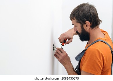 Man Installing Light Switch After Home Renovation. Electrician Mounting Electric Sockets On The White Wall. Electrician Wiring A New Build. Worker Installing Socket In New House.