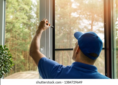 man installing mosquito net wire screen on house window