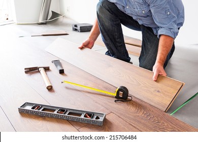 Man installing new laminated wooden floor - Shutterstock ID 215706484