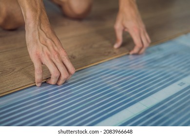 Man installing new wooden laminate flooring on a warm film floor. Infrared floor heating system under laminate floor