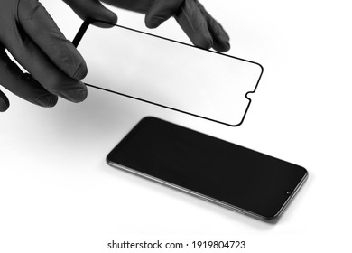 A Man Is Installing A Protective Glass On The Screen Of A Smartphone.