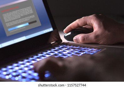 Man installing software in laptop in dark at night. Hacker loading illegal program or guy downloading files. Cyber security, piracy or virus concept.