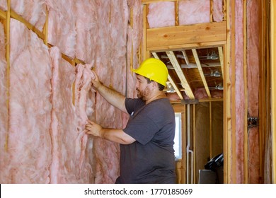 Man installing thermal insulation layer under the wall using mineral wool with fiberglass cold soft focus