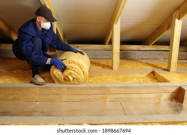 Man Installing Thermal Insulation Layer Under The Roof, Using Mineral Glass Wool 