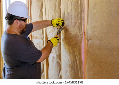 Man installing thermal insulation layer under the wall using mineral wool with fiberglass cold soft focus