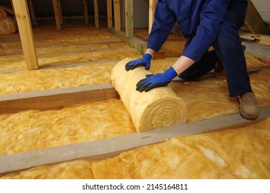 Man Installing Thermal Insulation Layer Under The Roof, Using Mineral Glass Wool 