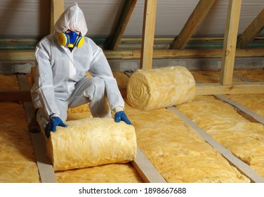 Man Installing Thermal Roof Insulation Layer Using Mineral Wool. 