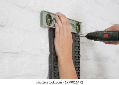 Man Installing Tool Board On The Wall. Plastic Pegboard Tool Organizer.