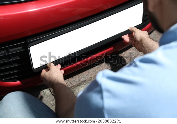 Man installing vehicle registration plate
outdoors, closeup. Mockup for
design