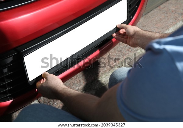 Man installing vehicle registration plate\
outdoors, closeup. Mockup for\
design