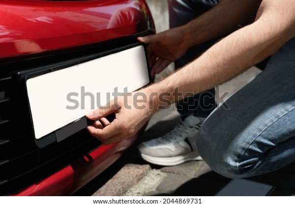 Man installing vehicle registration plate\
outdoors, closeup