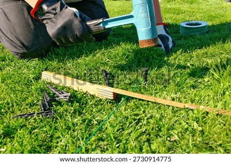 A man installs a cable and hammers a plastic pin into place to power a robotic lawn mower.