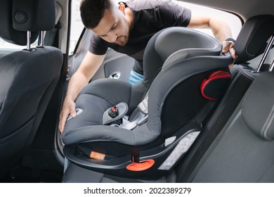 Man Installs A Child Car Seat In Car At The Back Seat. Responsible Father Thought About The Safety Of His Child