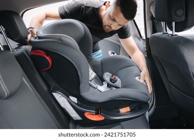 Man installs a child car seat in car at the back seat. Responsible father thought about the safety of his child. Man fasten seat belt on baby car seat - Powered by Shutterstock