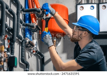A man installs a heating system in a house and checks the pipes with a wrench.