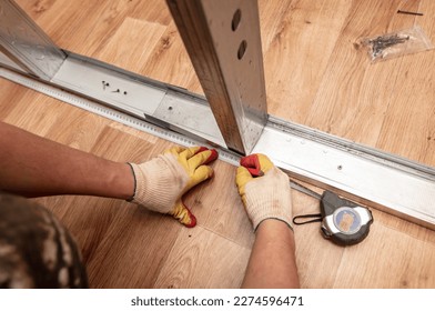 A man installs a metal profile for a wall in a room - Shutterstock ID 2274596471