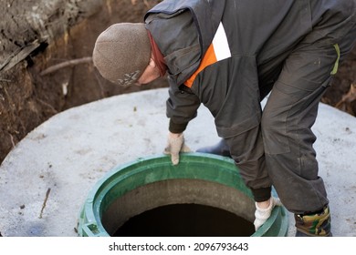 A Man Installs A Sewer Manhole On A Septic Tank Made Of Concrete Rings. Construction Of Sewer Networks In The Village.