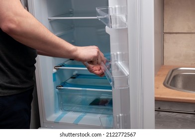 A Man Installs A Shelf In A New Refrigerator. High Quality Photo