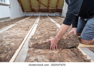 Man insulating the attic with rock wool. - Shutterstock ID 2033197670