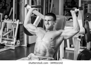 Man intensely performs exercises on the simulator in the gym.