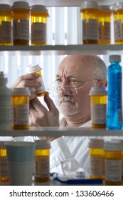 Man Intently Reading Label On Prescription Bottle