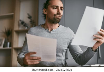 A man intently reviewing documents while working from home, conveying a sense of concentration and focus. Ideal for themes of remote work, business, and productivity. - Powered by Shutterstock