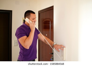 Man With Intercom Or Land Line Phone At Home