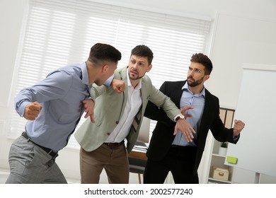 Man Interrupting Colleagues Fight At Work In Office